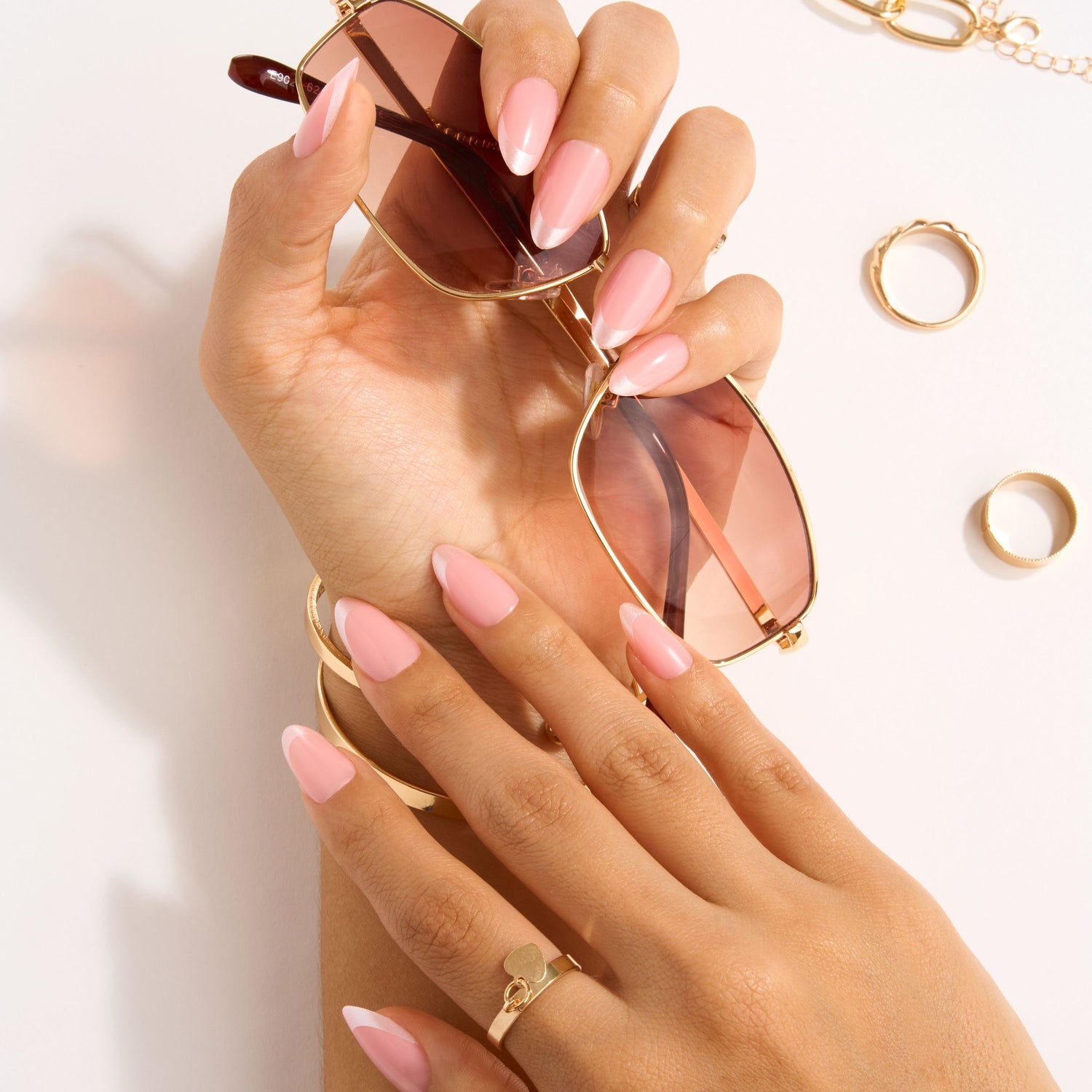 Hands wearing French Press Mani nail tips while holding sunglasses.